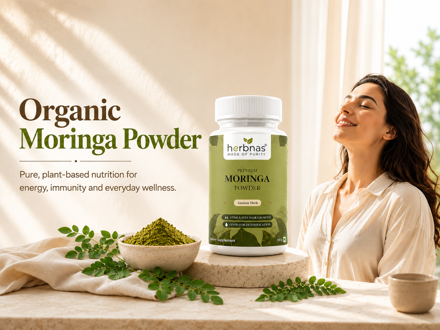 A bottle of herbnas Organic Moringa Powder is displayed on a table next to a bowl of green powder, fresh moringa leaves, and a woman in a white shirt looking up in a bright, sunlit room.